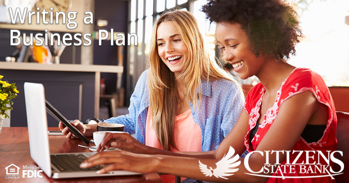 two smiling young women looking at a notebook computer